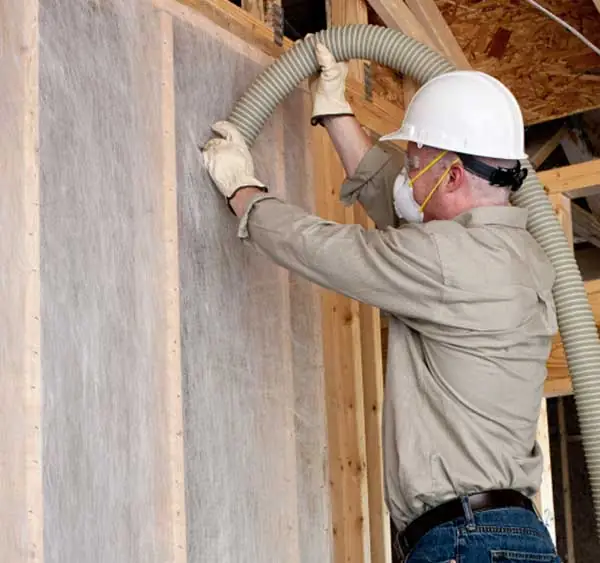Cellulose insulation installer, installing cellulose in home's walls.