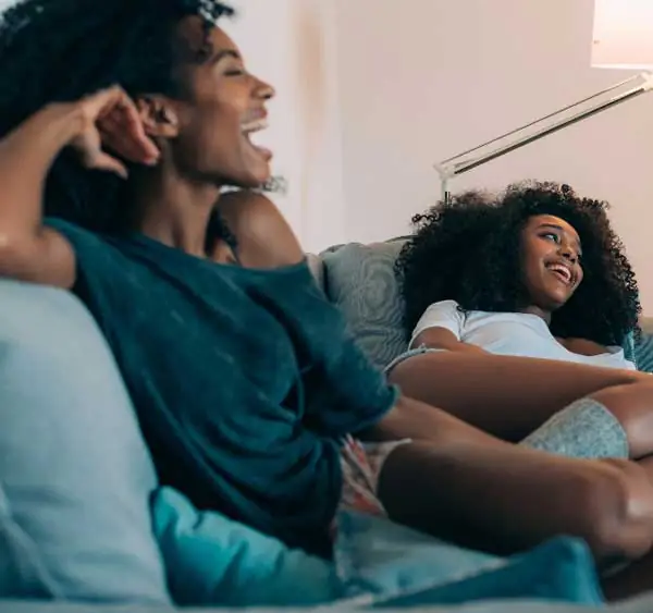 Mother and daughter laughing together on couch, in their insulated home.