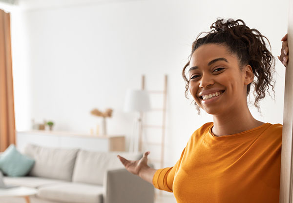 female homeowner opening her door to her home, welcoming her guests.