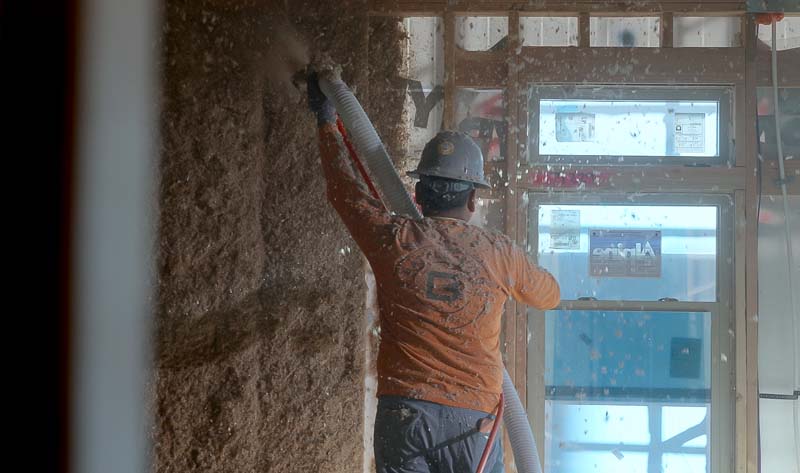 Battle Born Specialties installer spraying GreenFiber cellulose insulation into open wall framing during new home construction in Las Vegas.