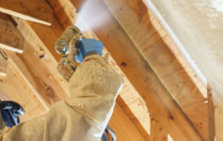 Battle Born Specialties technician applying spray foam insulation to roof deck rafters in Las Vegas, NV.
