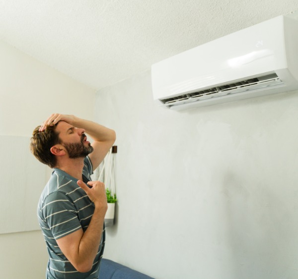 Man suffering in heat, despite AC being on.